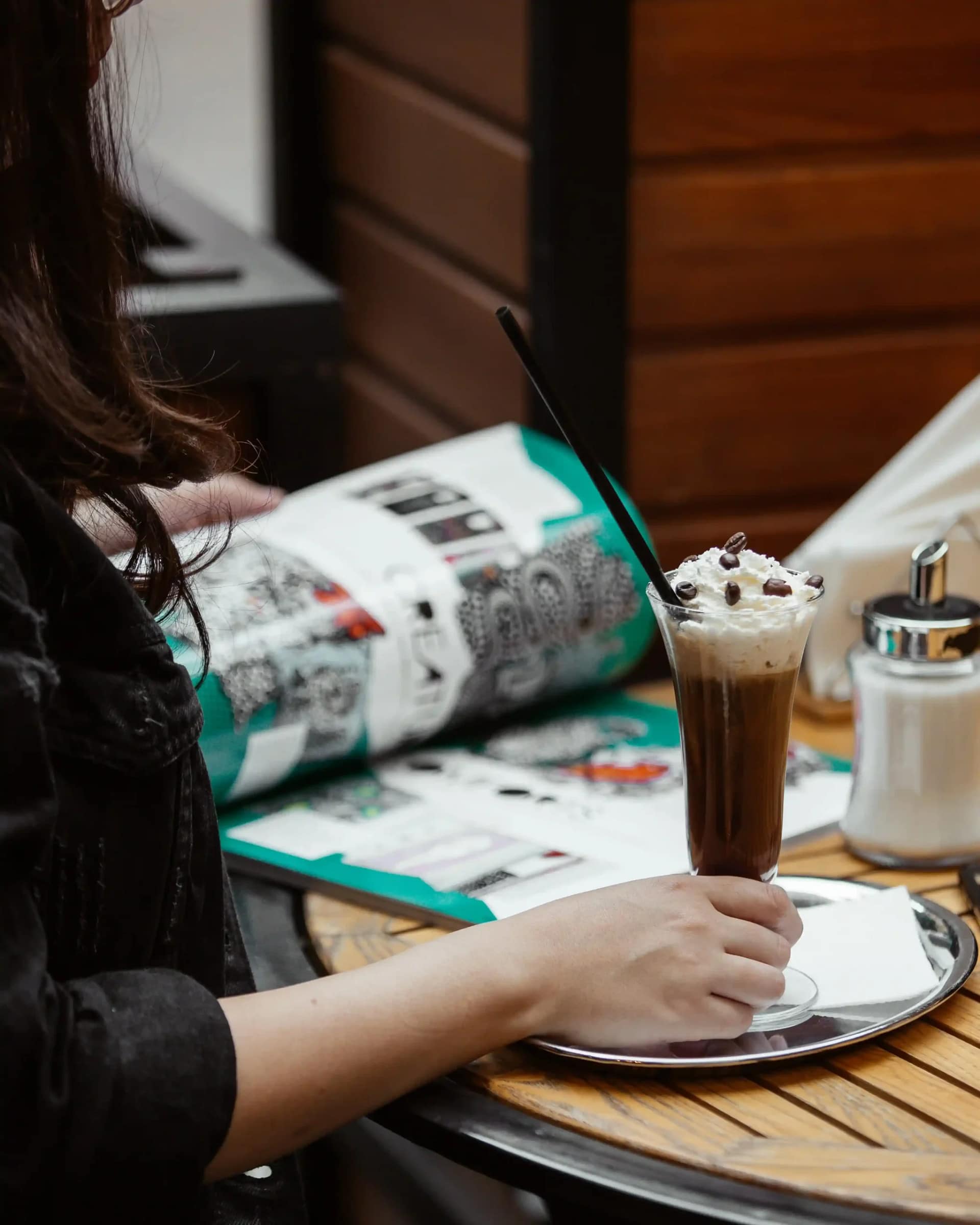 femme dans un restaurant avec magazine et un verre de cappuccino a la creme min 11zon